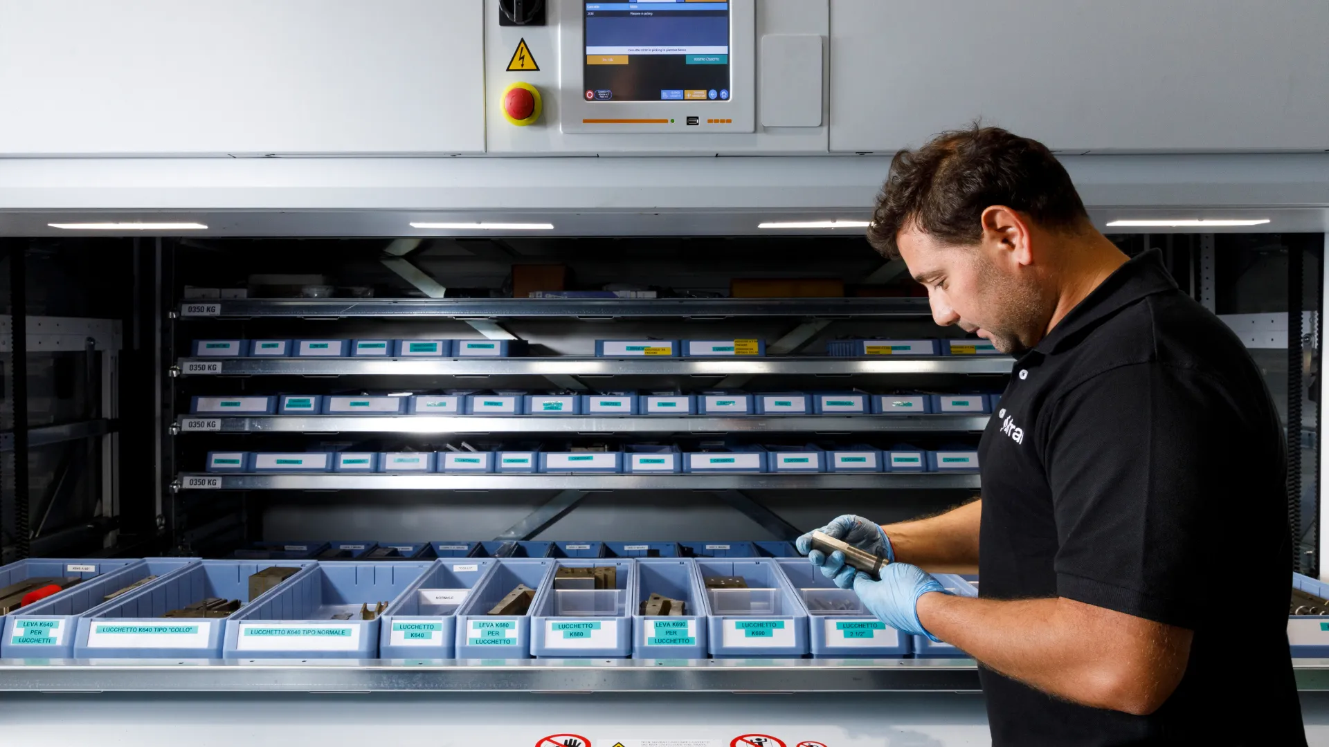 Operatore Sifral controlla un componente in metallo davanti al magazzino verticale automatico