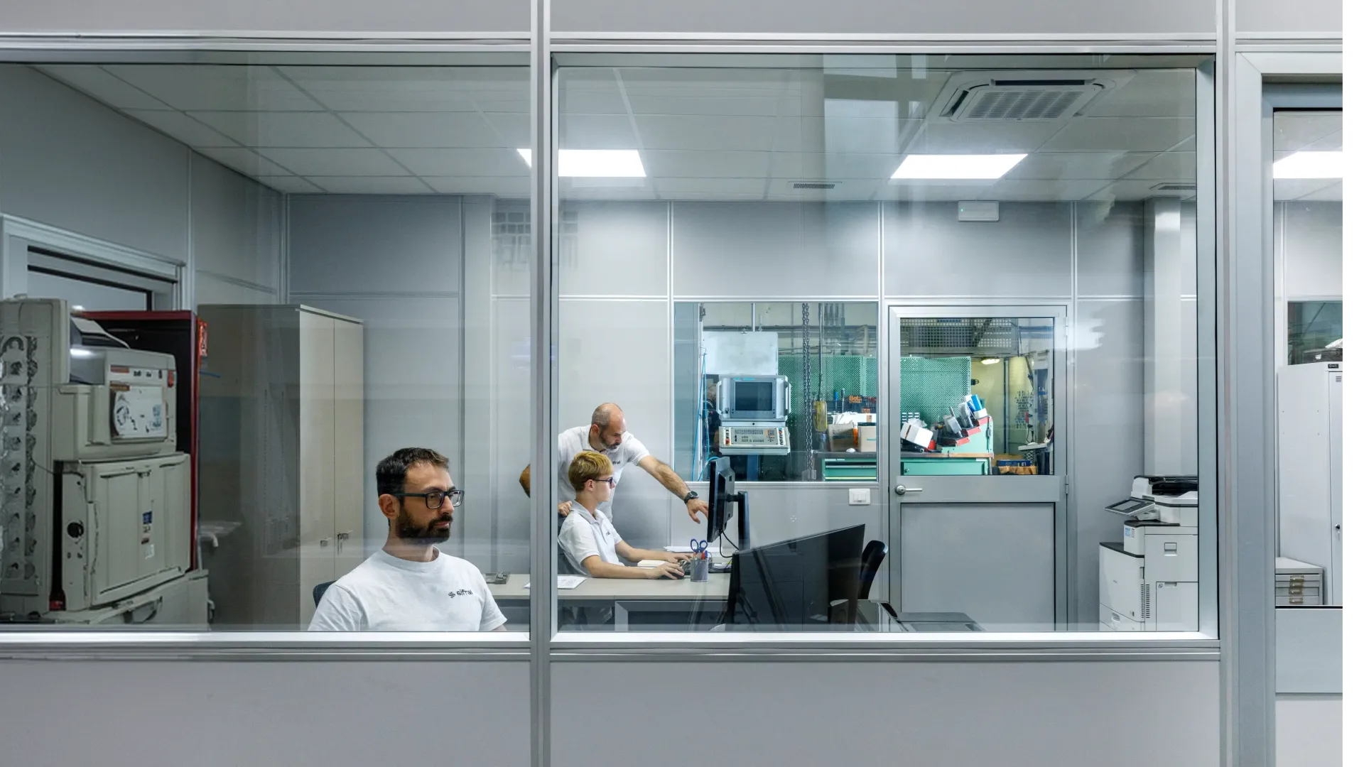 Tecnici al lavoro nell'ufficio tecnico vetrato di Sifral, affacciato sulla produzione